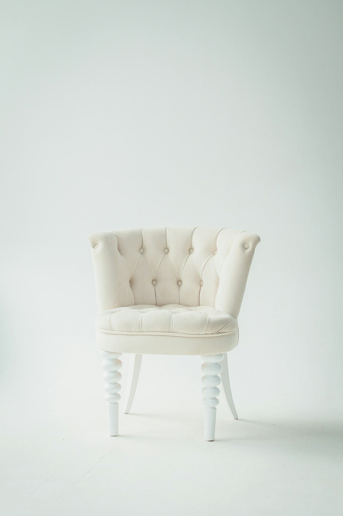 A cream button-tufted chair on a plain background